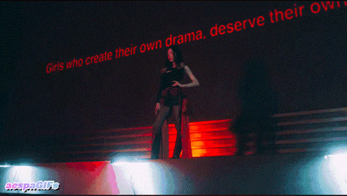 a woman stands in front of a wall that says girls who create their own drama deserve their own