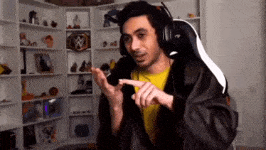 a man wearing headphones and a jacket is sitting in a gaming chair in a room .