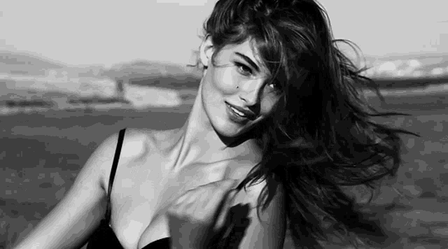 a woman in a black and white photo with her hair blowing in the wind