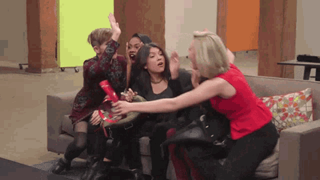 a group of women are sitting on a couch with one woman in a red shirt