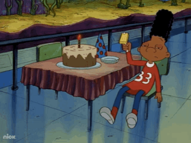 a cartoon character with the number 33 on his shirt sits at a table with a cake