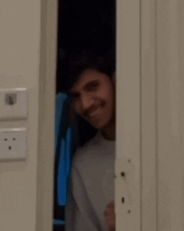 a man is peeking out from behind a door .