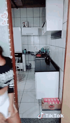 a woman is standing in a kitchen with a sign that says tik tok