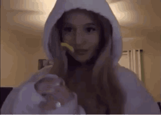 a woman in a white hoodie is holding a piece of food in her hand .