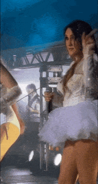 a woman in a white dress is standing on a stage with a microphone in her hand .