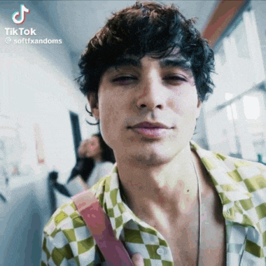 a man with curly hair is wearing a checkered shirt and a necklace