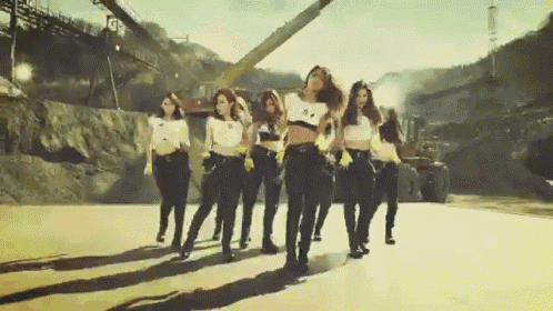 a group of women are dancing on a road in front of a building that says tgf