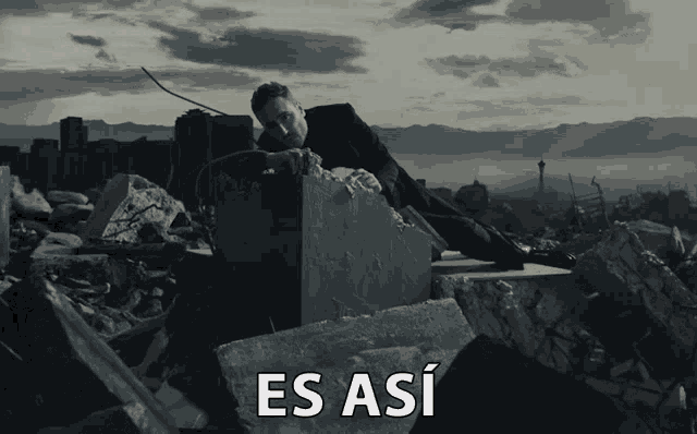 a man in a suit is laying on a pile of rocks with the caption es asi