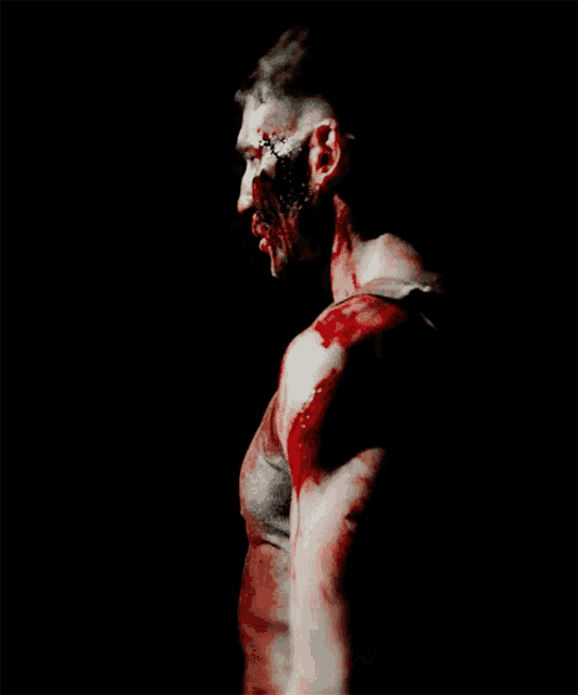 a man with blood on his face and shoulder in a dark room