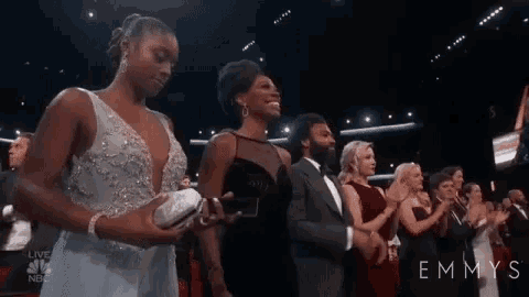 a group of people are standing in a line at an emmy awards show .