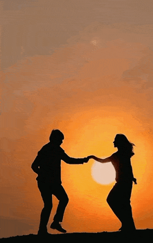 a man and a woman are holding hands in front of the sun
