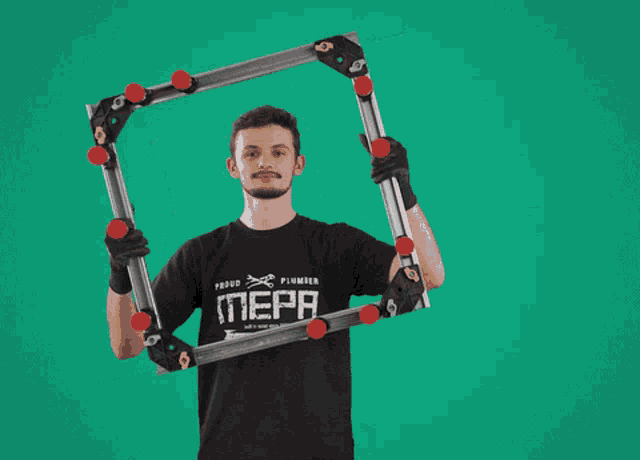 a man wearing a proud plumber nepa shirt is holding a metal frame
