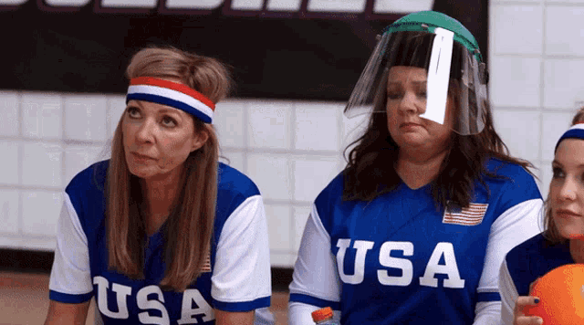 a woman wearing a usa jersey sits next to another woman wearing a headband