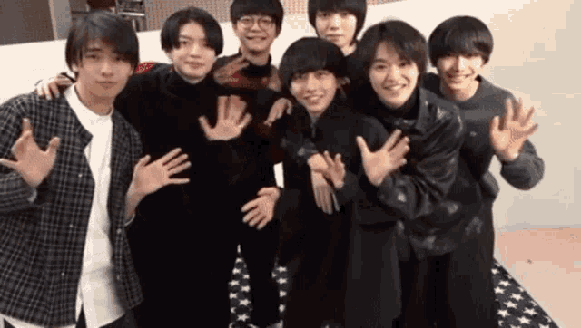 a group of young men are posing for a picture together and waving their hands .