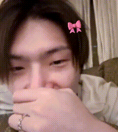a girl with a pink bow in her hair covering her mouth
