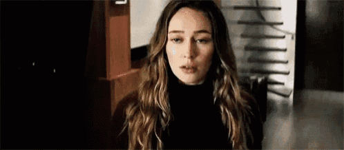 a woman is standing in a dark room wearing a black turtleneck .