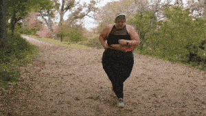a woman in a black top and black pants is running down a dirt path