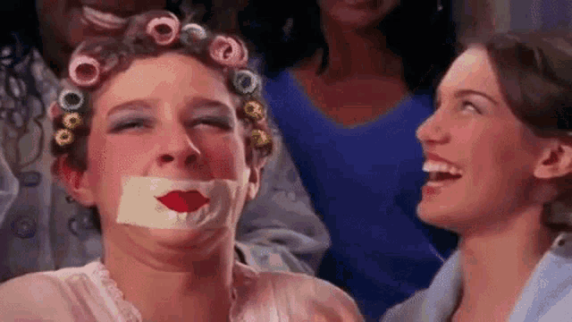 a woman with curlers on her head has duct tape on her mouth .