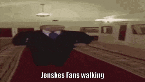 a man in a suit and tie is walking on a red carpet in a subway station .