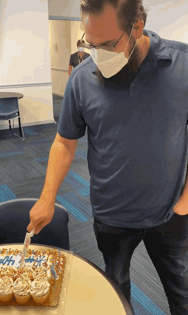a man wearing a mask and glasses is cutting a cake that says 50th on it