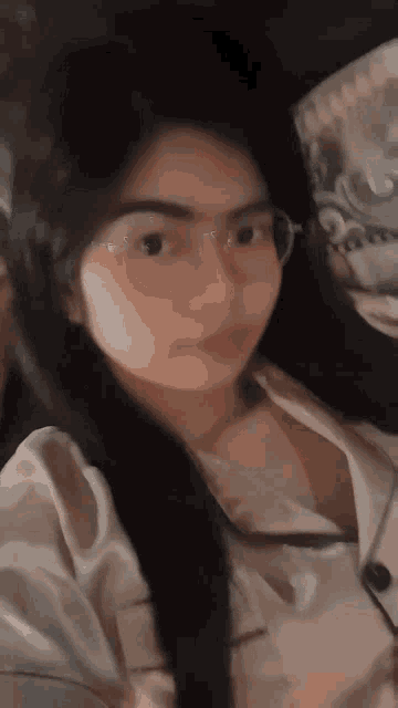 a woman wearing glasses and a white shirt is looking at the camera