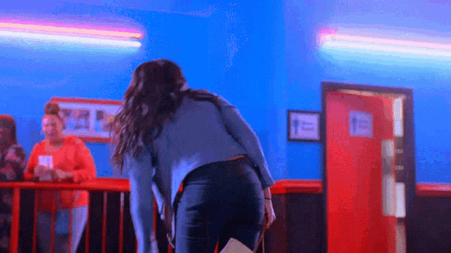 a woman is standing in a room with a red door and a sign that says 1 on it