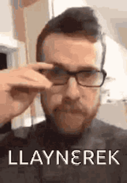 a man with a beard is wearing glasses and making a face .