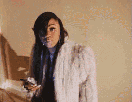 a woman in a fur coat smoking a cigarette and holding a cell phone