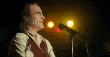 a man is standing in front of a microphone and singing into it .