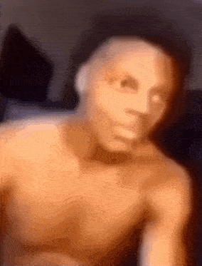 a man without a shirt is taking a selfie with his mouth open