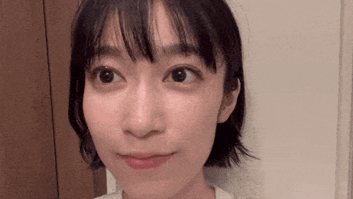 a close up of a woman 's face with short hair and bangs