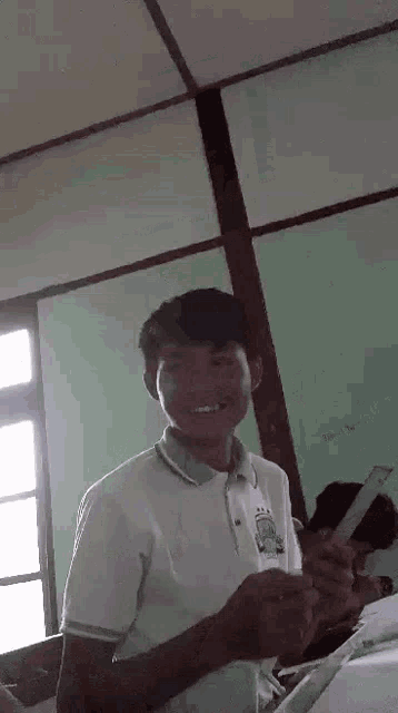 a young man in a white shirt is holding a ruler in a classroom .
