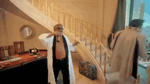 a man in a robe is holding a bottle of champagne while standing on a set of stairs .