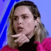 a woman in a pink jacket is making a funny face while pointing at something .