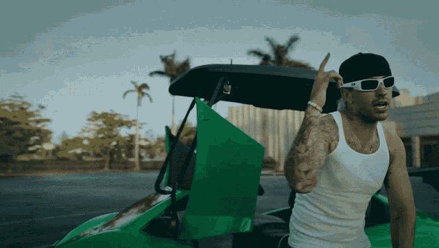 a man in a white tank top is sitting in a green vehicle