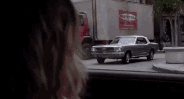 a ford mustang is driving down a city street