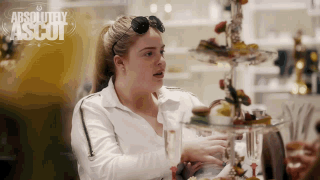 a woman sits at a table with a sign that says absolutely ascot on it