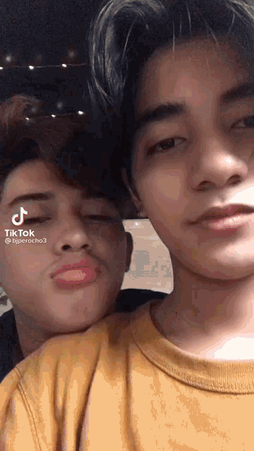 two young men are posing for a picture and one of them has a tik tok sticker on his face