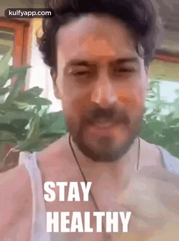a man with a beard is wearing a white tank top and a necklace .