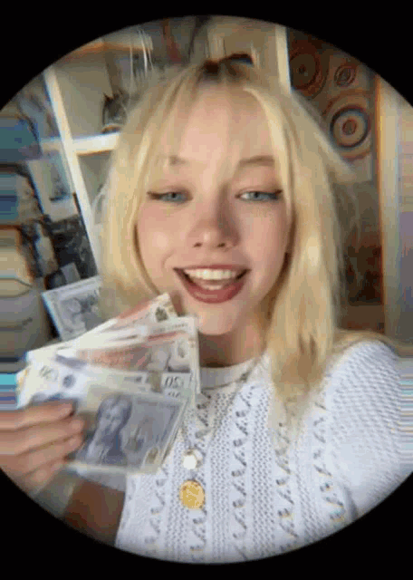 a blonde woman is holding a stack of money in her hands .