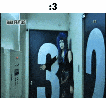 a woman with blue hair stands in front of a door with the number 3 on it