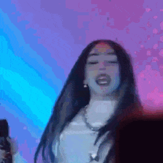 a woman with long hair is dancing in front of a blue and purple background .