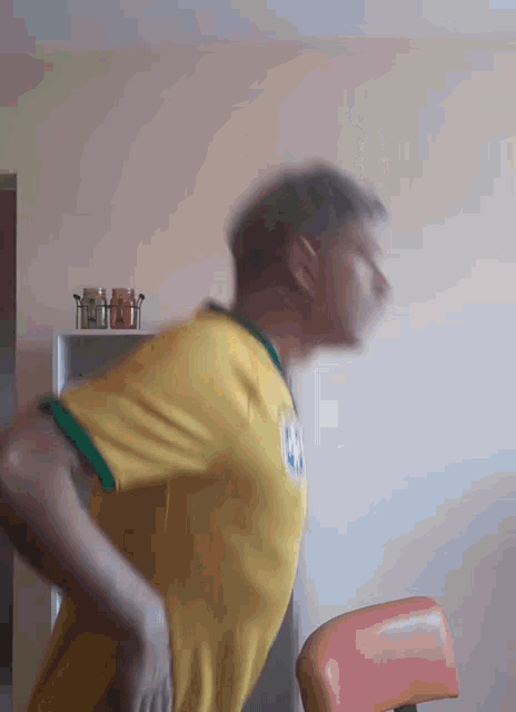 a blurry picture of a man in a yellow shirt with the letter g on his chest