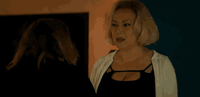a woman in a bra is standing in front of a mirror and looking at herself .