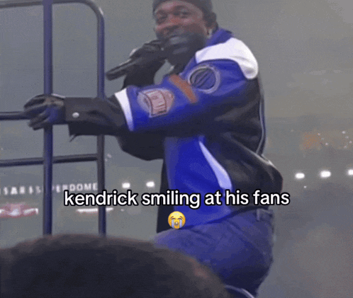 a man holding a microphone with the words kendrick smiling at his fans below him