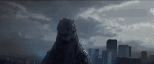 a giant monster is standing in the middle of a city in the dark .