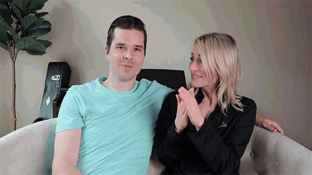 a man and a woman are sitting next to each other on a couch with a guitar case in the background