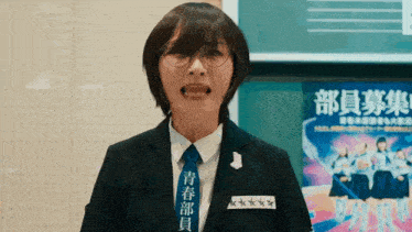 a woman wearing glasses and a blue tie has chinese writing on her shirt