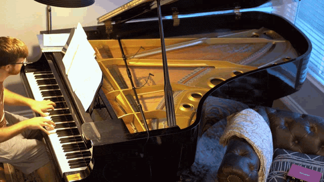 a man is playing a piano with a sheet of music on the shelf