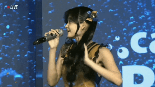 a woman singing into a microphone with the word live on the bottom right